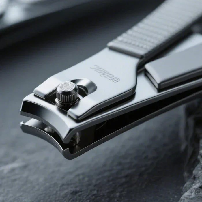 Close-up of stainless steel nail clippers with textured handle on a dark surface